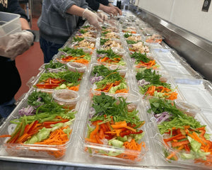 An image of a dozen packaged salads, full of colorful greens, carrots, bell peppers, red onion, and more.