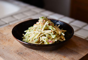 A plated dish featuring pale yellow and green cuts of apples and celery, sitting atop a kitchen counter.