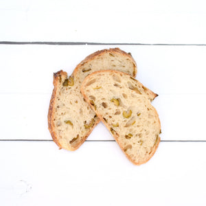 A close up flatlay of two pieces of fluffy, olive infused bread, with a rustic, golden crust.