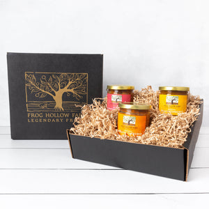 An elegant gift box with a gold embossed tree, featuring a colorful conserve trio, showcasing delicious fruit preserves.
