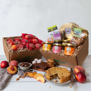 Two gift baskets with an assortment of handmade jams, baked goods, nuts, and juicy peaches and nectarines.