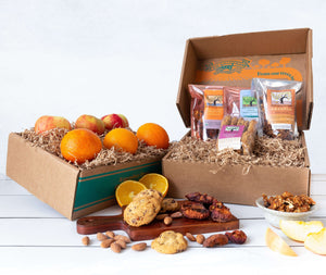 Two rustic raft gift boxes, one filled with crisp apples and vibrant citrus, and the other filled with artfully packaged Frog Hollow snacks.