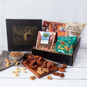 An elegant gift box with a gold embossed tree, filled with artfully packaged sun-dried fruit, almonds, walnuts, and cashews.