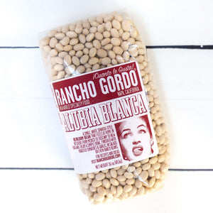 Small white beans contained in a sealed bag on a white background