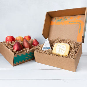 Two rustic craft gift baskets featuring juicy pears and crisp apples, and artfully packaged Point Reyes blue cheese and Bellwether Farms Carmody Cheese.