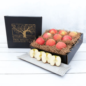 An elegant gift box with a gold embossed tree filled with crisp apples.