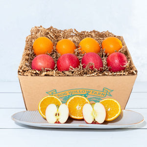 A rustic craft gift basket featuring vibrant citrus oranges and crisp apples. 