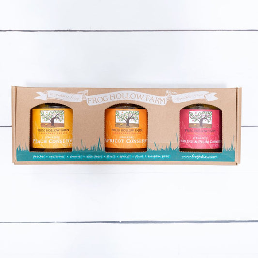 A close up image of three colorful fruit conserves, artfully packaged in a Frog Hollow gift set box on a white background.