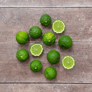A flat lay image of limes on a rustic wooden table, showcasing their bright green skin and juicy pulp.