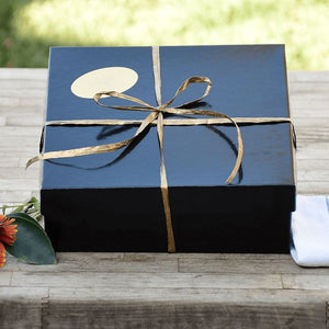 A close up image of an artfully wrapped gift box on a wooden table.
