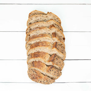 A flatlay image of a loaf of rustic, artisan bread with crunchy golden crust, cut into even slices, showcasing the fluffy interior of the loaf.