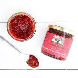 A flat lay of a jar containing a bright red Nectarine and plum conserve with a Frog Hollow label, next to spoonful of conserve.