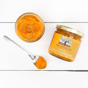 A flat lay of a jar containing a yellow peach conserve with a Frog Hollow label, next to spoonful of peach conserve.