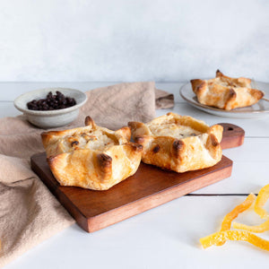 A visually appealing display of sweet-risotto, golden pastry tartlets, on a wooden serving board, surrounded by candied fruit.